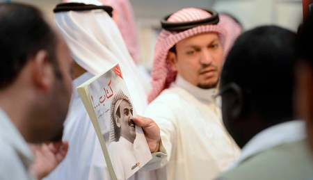 A man shows a book by Saudi writer and poet Al-Rotayyan during the Riyadh Book Fair in Riyadh