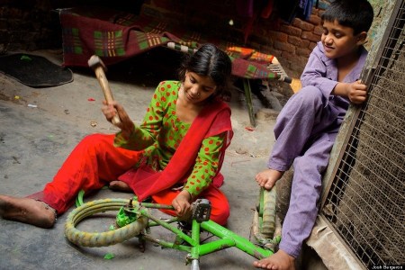 Children dismantle a bicycle to sell for parts.