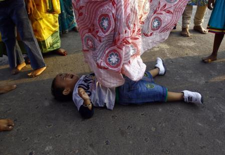 A Hindu woman steps over a child in a ritual seeking blessings for the child from the Sun god Surya during the Chatt Puja festival in Kolkata