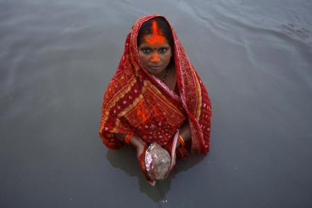 A devotee offers prayers to the setting sun during the "Chhat" festival at Bagmati River in Kathmandu