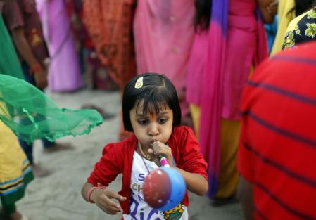 A girl blows a balloon pipe during the Hindu religious festival of Chatt Puja in New Delhi