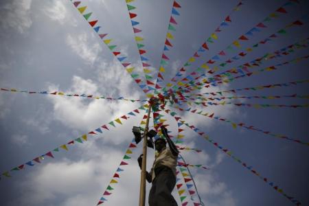 A man fits a light on a bamboo pole during the "Chhat" festival near the bank of Bagmati River in Kathmandu