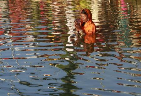 A woman worships the Sun god Surya in the waters of the Laxmi Narayan lake during the Hindu religious festival of Chatt Puja in Agartala