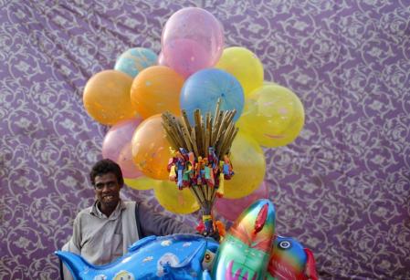 A vendor selling balloons waits for customers on the banks of the river Yamuna during the Hindu religious festival of Chatt Puja in New Delhi