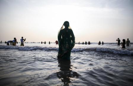 A Hindu devotee prays while standing in the waters of the Arabian Sea as she worships the Sun god Surya during the Hindu religious festival "Chatt Puja" in Mumbai
